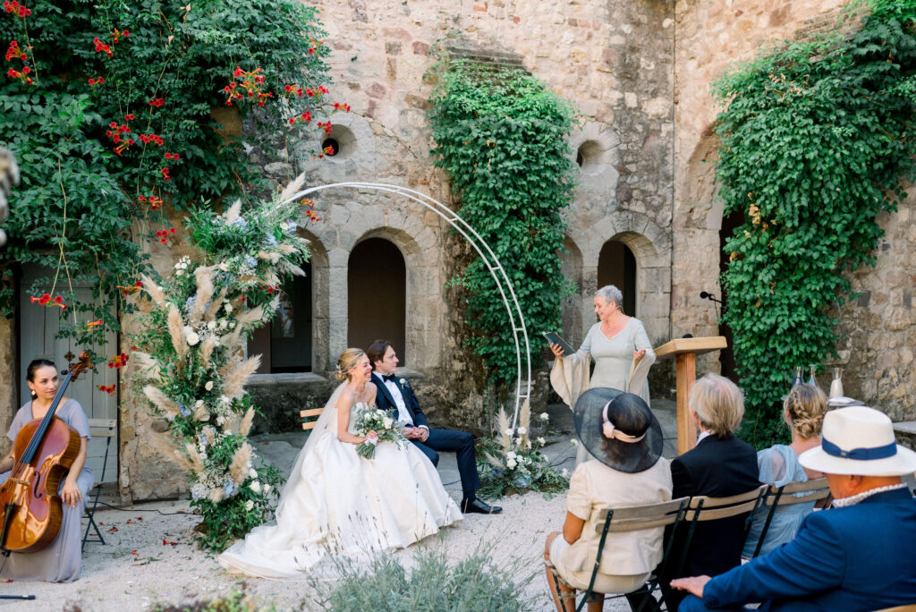 Wedding ceremony in France with floral arch and musician